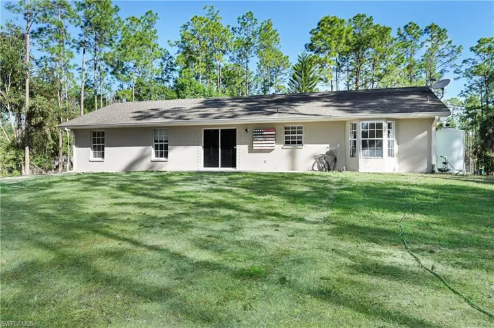 Back of house featuring stucco siding and a yardLawn AI generated