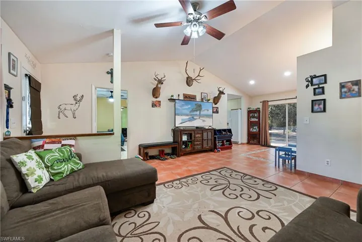 Living area with ceiling fan, light tile patterned floors, and a high ceiling