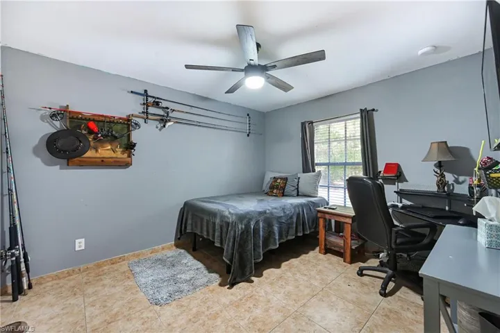 Bedroom with an office area, a ceiling fan, and light tile patterned floors