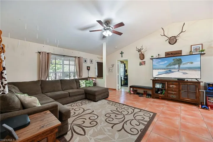 Living area featuring lofted ceiling, a ceiling fan, and light tile patterned floors