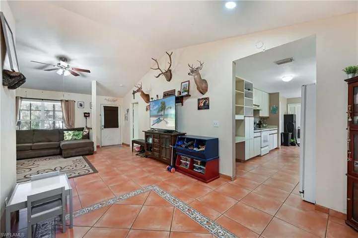 Living room featuring light tile patterned floors, lofted ceiling, and ceiling fan