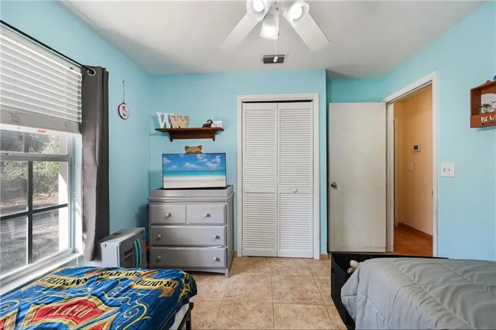 Bedroom featuring a closet, light tile patterned floors, and ceiling fan