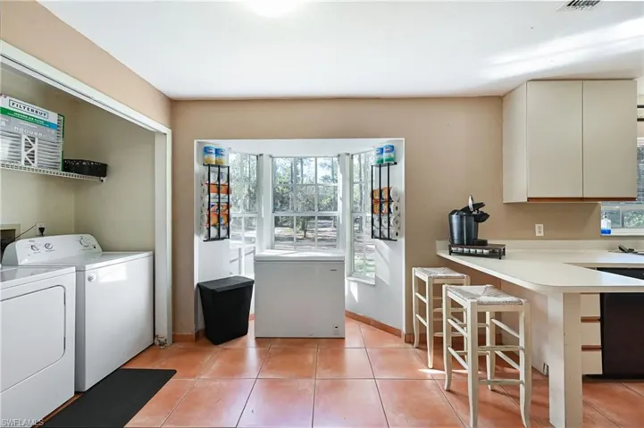 Laundry area with washer and clothes dryer and light tile patterned flooring