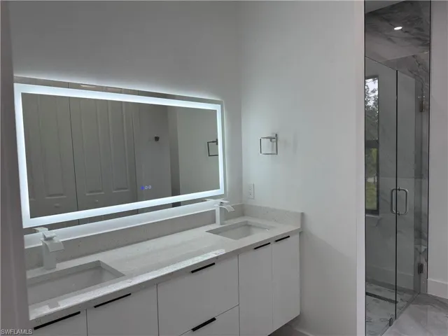 Full bathroom with double vanity, a marble finish shower, and marble finish floors