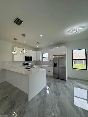 Kitchen with modern cabinets, refrigerator, white cabinets, light countertops, and a peninsula