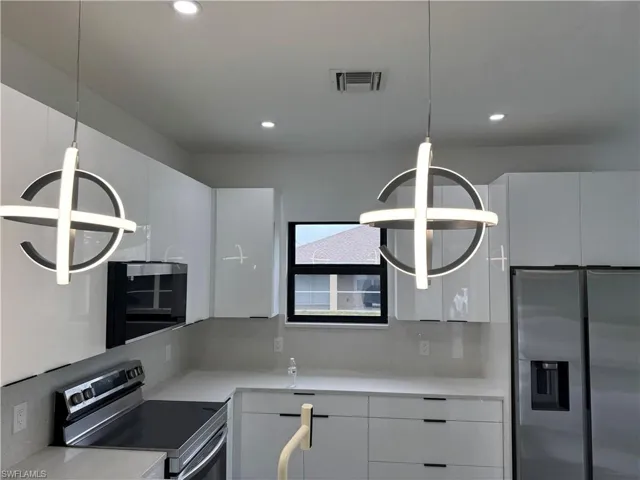 Kitchen with stainless steel appliances, recessed lighting, light countertops, white cabinetry, and modern cabinets