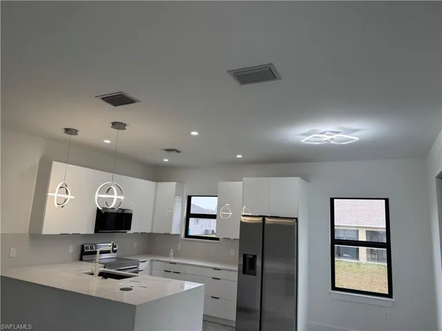 Kitchen with stainless steel appliances, a peninsula, modern cabinets, white cabinets, and recessed lighting