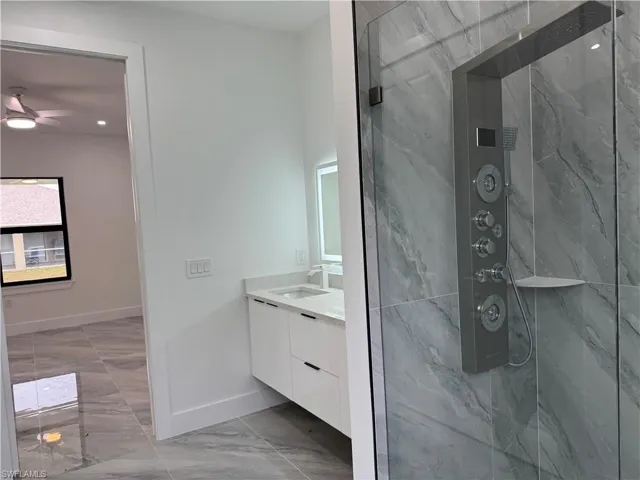 Full bath with marble finish floors, vanity, a marble finish shower, and a ceiling fan