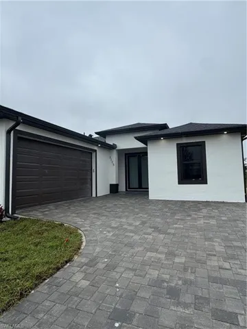 View of front facade with stucco siding, a garage, and driveway