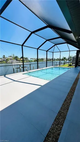 Screened lanai with a rectangular pool, concrete decking, and a gravel accent strip