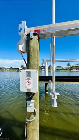 Waterfront access with a boat lift system, featuring a wooden pilings and aluminum framework