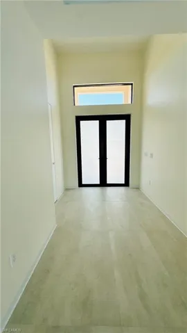 Entryway featuring a double door with opaque glass, transom window, and light-toned flooring