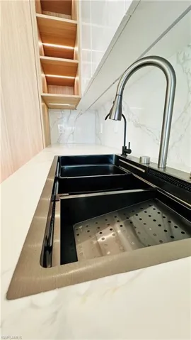 Integrated workstation sink with a gooseneck faucet, white countertop, and marble-look backsplash