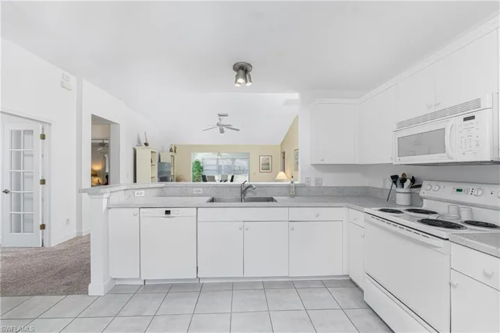 Kitchen with sink, white cabinetry, ceiling fan, kitchen peninsula, and white appliances
