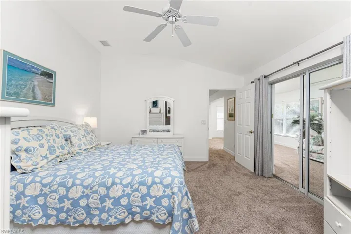 Carpeted bedroom with ceiling fan and lofted ceiling