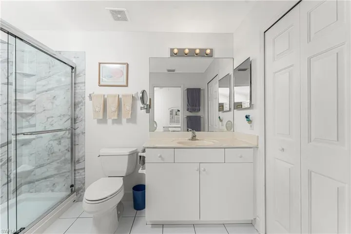 Bathroom featuring vanity, tile patterned flooring, a shower with door, and toilet