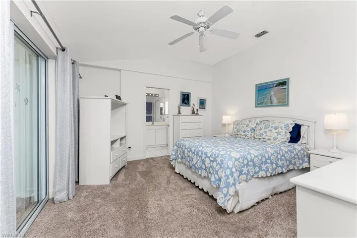 Bedroom featuring lofted ceiling, connected bathroom, light colored carpet, and ceiling fan
