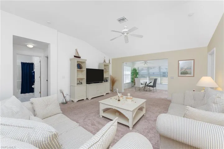 Carpeted living room with lofted ceiling and ceiling fan