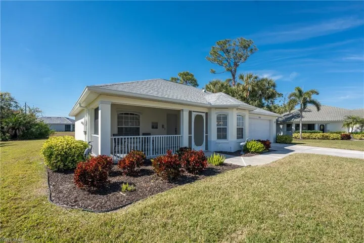 Single story home featuring a garage, covered porch, and a front yard
