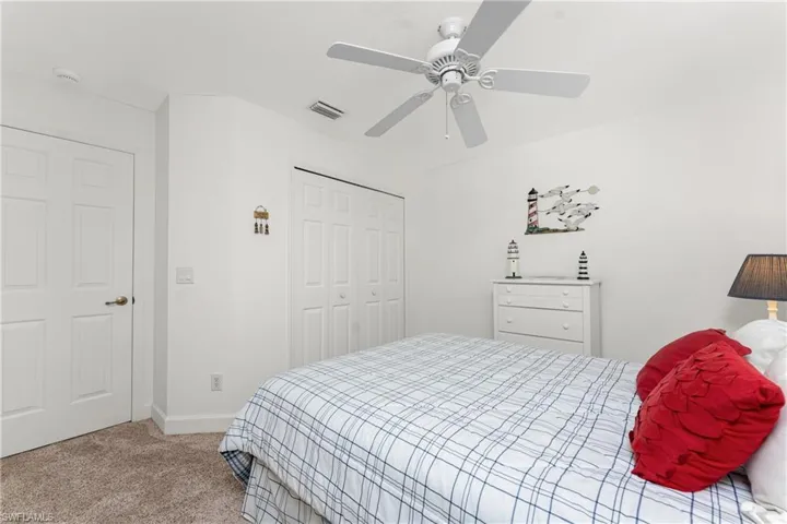 Bedroom with ceiling fan, light colored carpet, and a closet