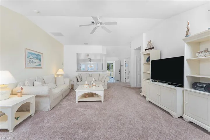 Carpeted living room featuring lofted ceiling and ceiling fan