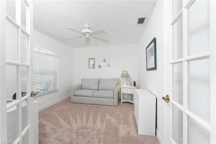 Living room featuring french doors, light colored carpet, and ceiling fan