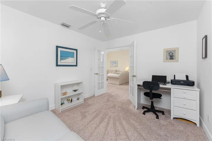 Office area featuring french doors, ceiling fan, and light carpet