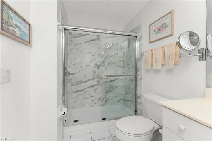Bathroom with walk in shower, tile patterned floors, vanity, and toilet