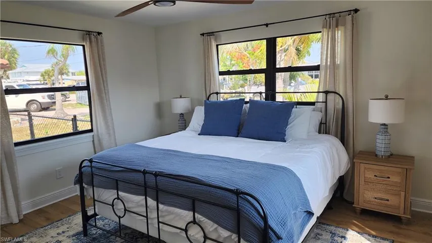 Bedroom featuring multiple windows, ceiling fan, and dark wood-type flooring