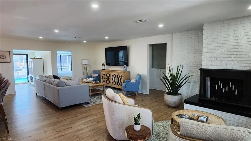 Living room featuring brick wall, a brick fireplace, and LVP flooring