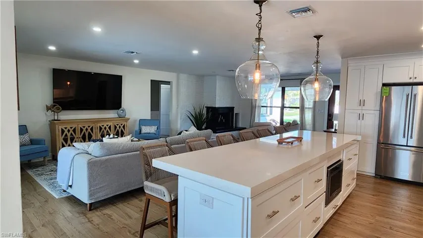 Kitchen featuring white shaker cabinet, a massive kitchen island, beverage cooler and stainless steel fridge