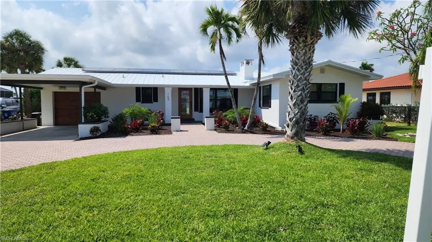 Ranch-style home featuring a garage, a front lawn, a carport, and central AC unit