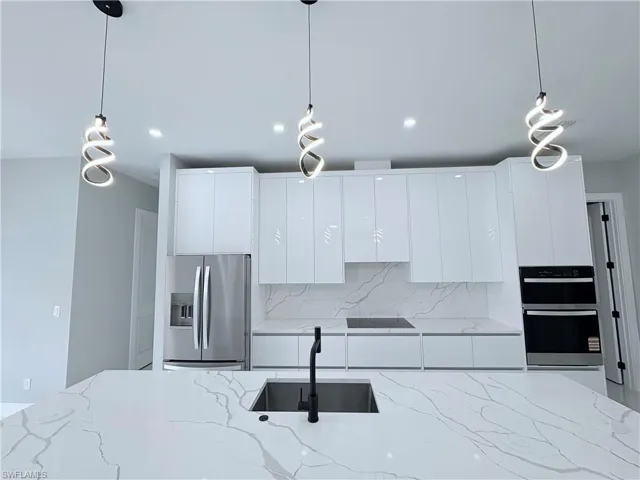 Kitchen featuring pendant lighting, stainless steel appliances, and light stone counters