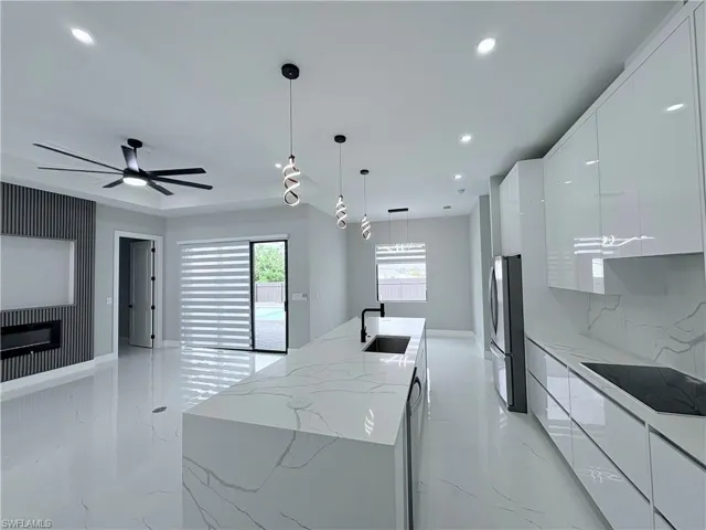 Kitchen featuring a kitchen island with sink, modern cabinets, black electric cooktop, and white cabinetry