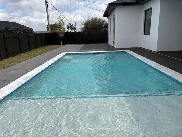 View of swimming pool featuring patio surround and a fenced backyard