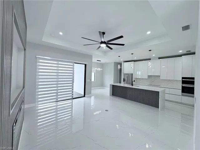 Kitchen with modern cabinets, white cabinetry, ceiling fan, a large island, and tasteful backsplash