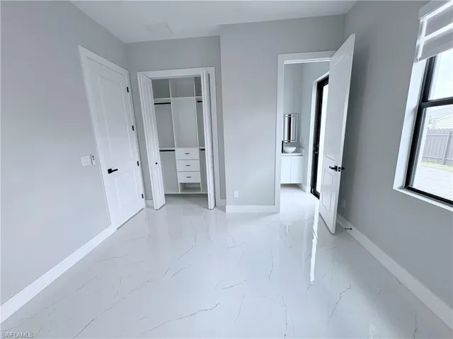 Unfurnished bedroom with light marble finish floors and a closet