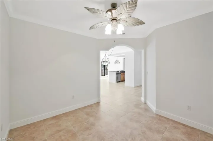 Den with crown molding, custom ceiling fan and arched walkway