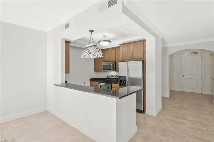 Kitchen with granite counter tops, stainless steel appliances, solid wood cabinetry, crown molding and custom lighting