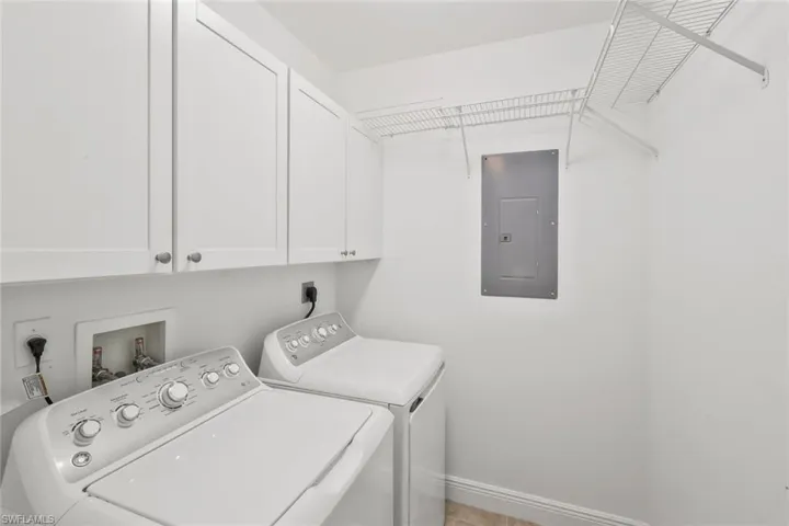 Laundry area with electric panel, washer and clothes dryer, and extra cabinets