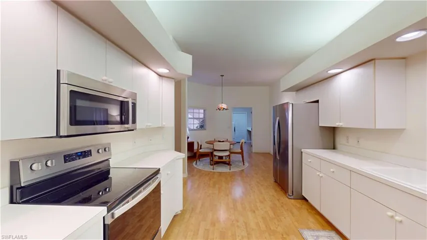 Kitchen with appliances with stainless steel finishes, decorative light fixtures, light countertops, recessed lighting, and light wood-style floors