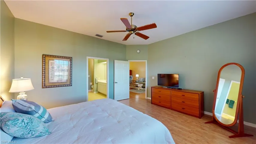 Bedroom with light wood finished floors, ceiling fan, and ensuite bathroom