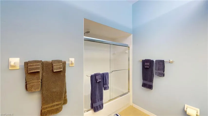 Bathroom featuring combined bath / shower with glass door and tile patterned flooring
