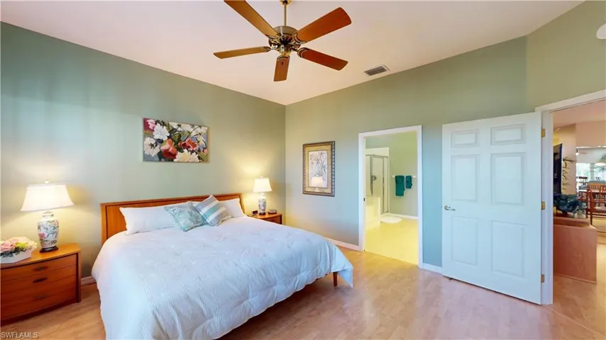 Bedroom with light wood-style flooring, connected bathroom, and ceiling fan