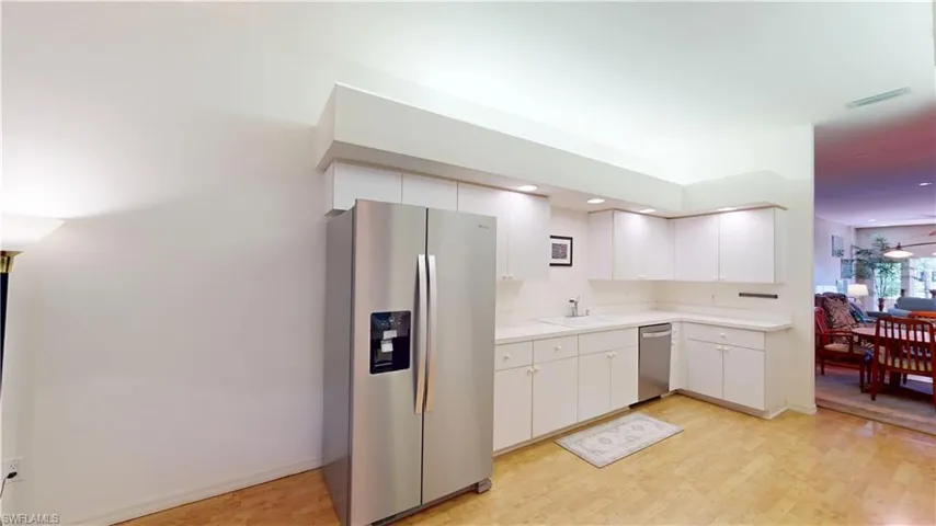 Kitchen featuring appliances with stainless steel finishes, white cabinetry, light wood-style floors, and tile counters