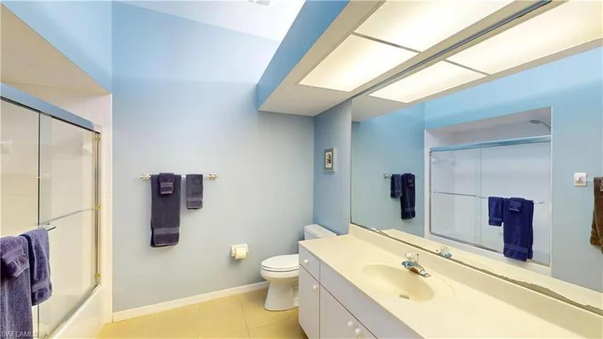 Full bath featuring vanity, light tile patterned floors, and shower / bath combination with glass door