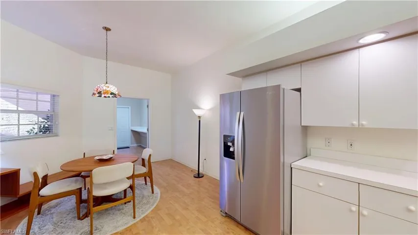 Kitchen featuring stainless steel fridge with ice dispenser, light countertops, white cabinets, pendant lighting, and light wood-type flooring