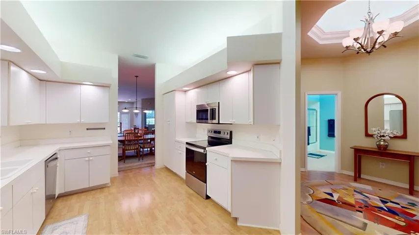 Kitchen with a chandelier, hanging light fixtures, stainless steel appliances, light countertops, and recessed lighting