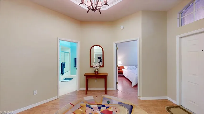 Entrance foyer with light wood-style floors, a chandelier, and a towering ceiling