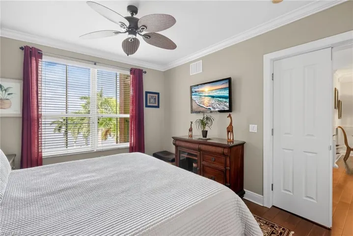Bedroom with crown molding, dark wood finished floors, and a ceiling fan